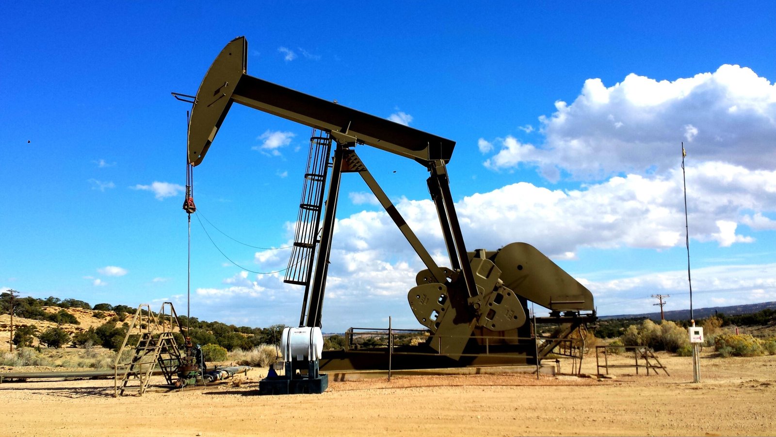 Oil pump jack silhouetted against a dramatic red sunset, symbolising oil market volatility