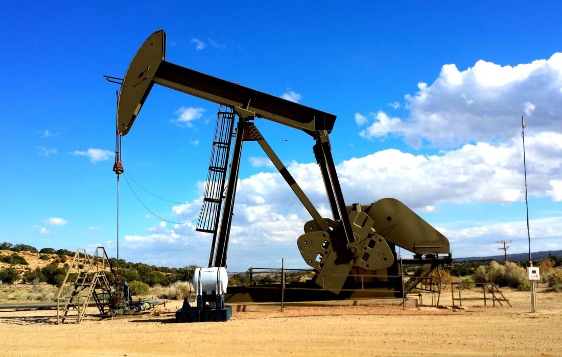 Oil pump jack silhouetted against a dramatic red sunset, symbolising oil market volatility