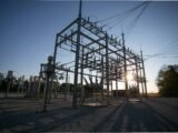 Data center transformer shortage: a high-voltage electrical substation with transformers and switchgear silhouetted at sunset.