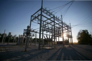 Data center transformer shortage: a high-voltage electrical substation with transformers and switchgear silhouetted at sunset.
